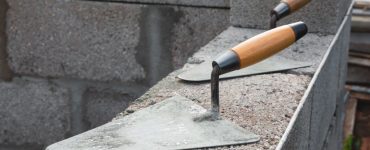 Deux truelles posées sur un mur en béton en construction