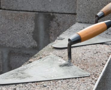 Deux truelles posées sur un mur en béton en construction