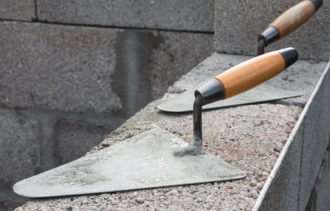 Deux truelles posées sur un mur en béton en construction