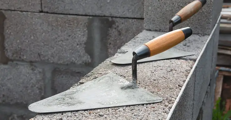 Deux truelles posées sur un mur en béton en construction