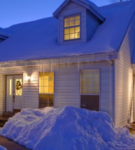 Une maison blanche couverte de neige, avec les lumières allumées