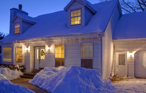 Une maison blanche couverte de neige, avec les lumières allumées