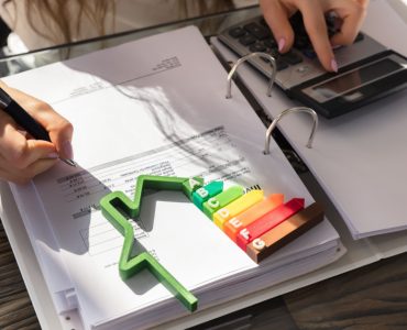 Une femme utilisant une calculatrice, avec une maquette de l’étiquette énergie sur la table