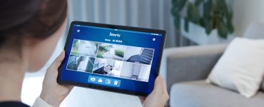 Une fille en train de visualiser les caméras de surveillance d'une maison à l'aide de sa tablette