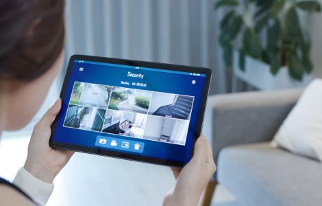 Une fille en train de visualiser les caméras de surveillance d'une maison à l'aide de sa tablette