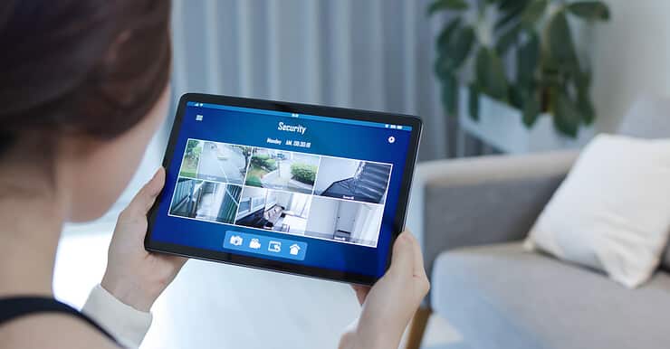 Une fille en train de visualiser les caméras de surveillance d'une maison à l'aide de sa tablette