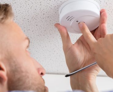 Un homme installe un détecteur de fumée au plafond