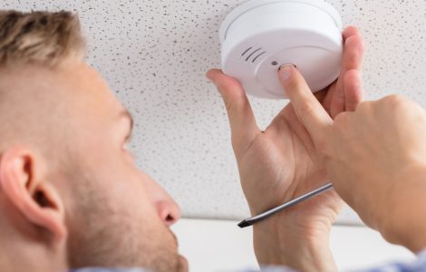 Un homme installe un détecteur de fumée au plafond