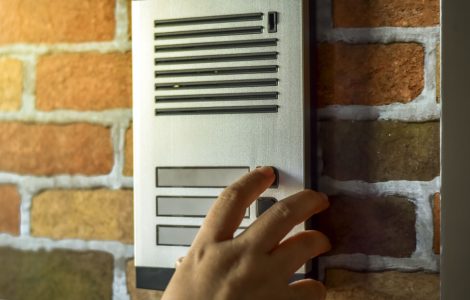 Zoom sur la main d'une personne appuyant sur un bouton de l'interphone