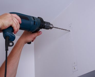 Un homme perce un trou dans le mur blanc