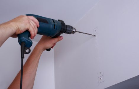 Un homme perce un trou dans le mur blanc