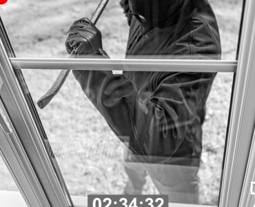 Un cambrioleur cagoulé tente d’entrer par effraction par la fenêtre vitrée d’une maison