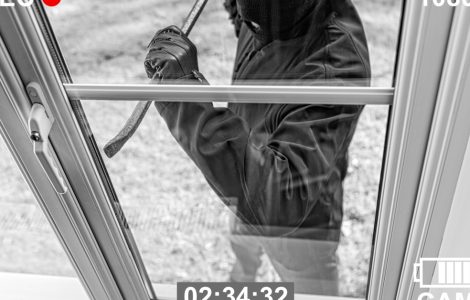 Un cambrioleur cagoulé tente d’entrer par effraction par la fenêtre vitrée d’une maison