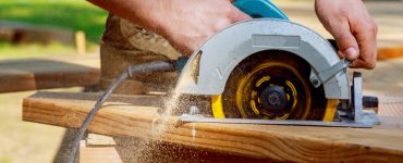 Un homme découpe une planche en bois avec une scie circulaire
