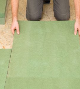 Focus sur un homme posant une planche d'isolation en fibre de bois naturel vert