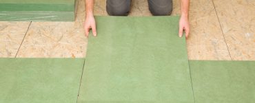 Focus sur un homme posant une planche d'isolation en fibre de bois naturel vert