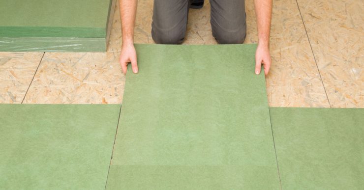 Focus sur un homme posant une planche d'isolation en fibre de bois naturel vert