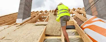 Un homme installant un matériau d'isolation de toit sur le toit d'une maison en construction