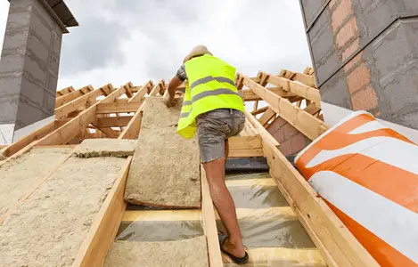 Un homme installant un matériau d'isolation de toit sur le toit d'une maison en construction