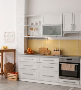 Une cuisine aux placards blancs avec quelques meubles en bois à côté