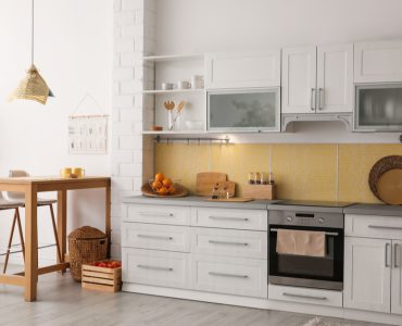 Une cuisine aux placards blancs avec quelques meubles en bois à côté