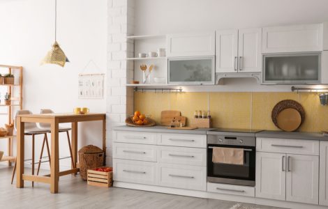 Une cuisine aux placards blancs avec quelques meubles en bois à côté