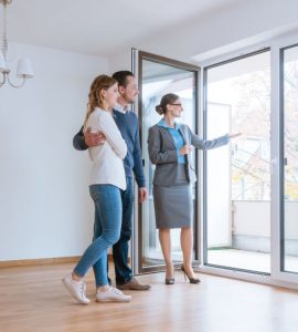Une femme fait visiter une maison à un jeune couple qui envisage de louer ou acheter
