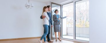 Une femme fait visiter une maison à un jeune couple qui envisage de louer ou acheter