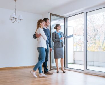 Une femme fait visiter une maison à un jeune couple qui envisage de louer ou acheter
