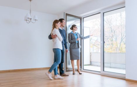 Une femme fait visiter une maison à un jeune couple qui envisage de louer ou acheter