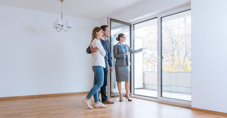 Une femme fait visiter une maison à un jeune couple qui envisage de louer ou acheter