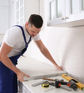 Un artisan installe un nouveau plan de travail dans une cuisine