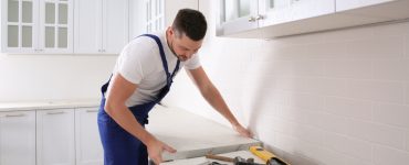 Un artisan installe un nouveau plan de travail dans une cuisine
