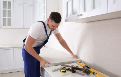Un artisan installe un nouveau plan de travail dans une cuisine