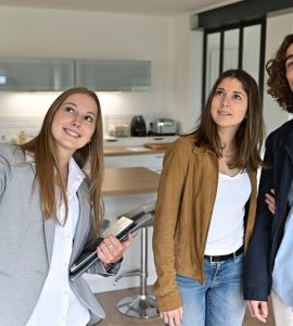 Une femme fait visiter un appartement à un jeune couple