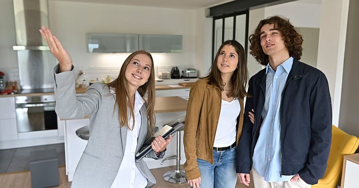 Une femme fait visiter un appartement à un jeune couple