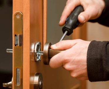 Mains d'un homme réglant la poignée d'une porte en bois