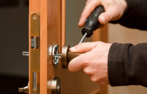 Mains d'un homme réglant la poignée d'une porte en bois