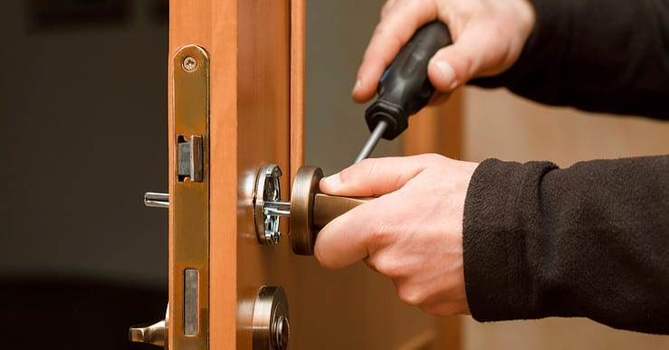 Mains d'un homme réglant la poignée d'une porte en bois