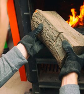 L'homme charge le bois de chauffage dans la chaudière à combustible