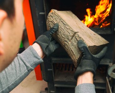 L'homme charge le bois de chauffage dans la chaudière à combustible