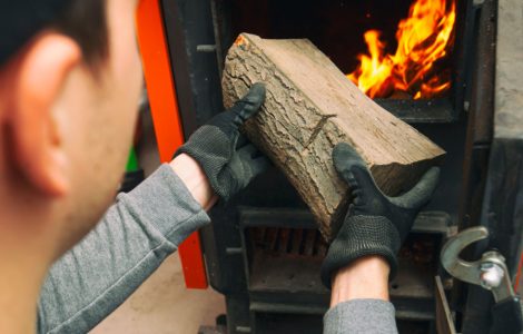 L'homme charge le bois de chauffage dans la chaudière à combustible