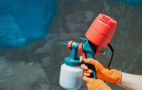 Un homme peint un mur en bleu à l’aide d’un pistolet à air