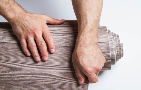 Zoom sur les mains d'un homme enroulant un rouleau de linoléum marron