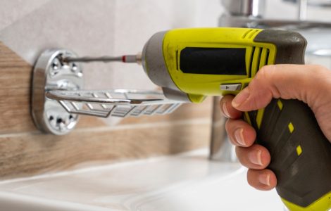 Zoom sur la main d'un homme en train de percer un carreau avec une perceuse électrique