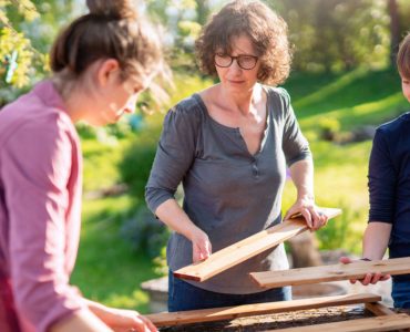 Une mère et ses deux enfants assemblant un panneau de bois