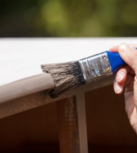 Zoom sur la main d'une femme peignant un vieux placard en bois en blanc