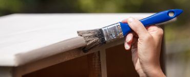 Zoom sur la main d'une femme peignant un vieux placard en bois en blanc