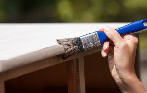 Zoom sur la main d'une femme peignant un vieux placard en bois en blanc