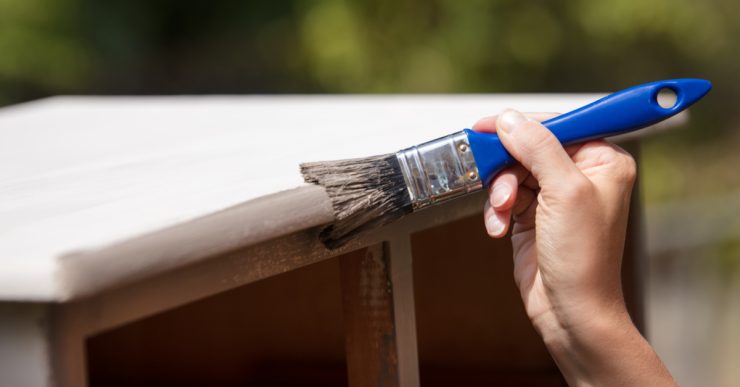 Zoom sur la main d'une femme peignant un vieux placard en bois en blanc